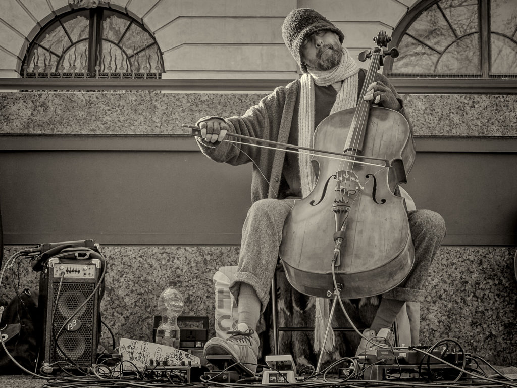 Straßenmusiker spielt ein Streichinstrument in der Innenstadt – authentische Straßenfotografie