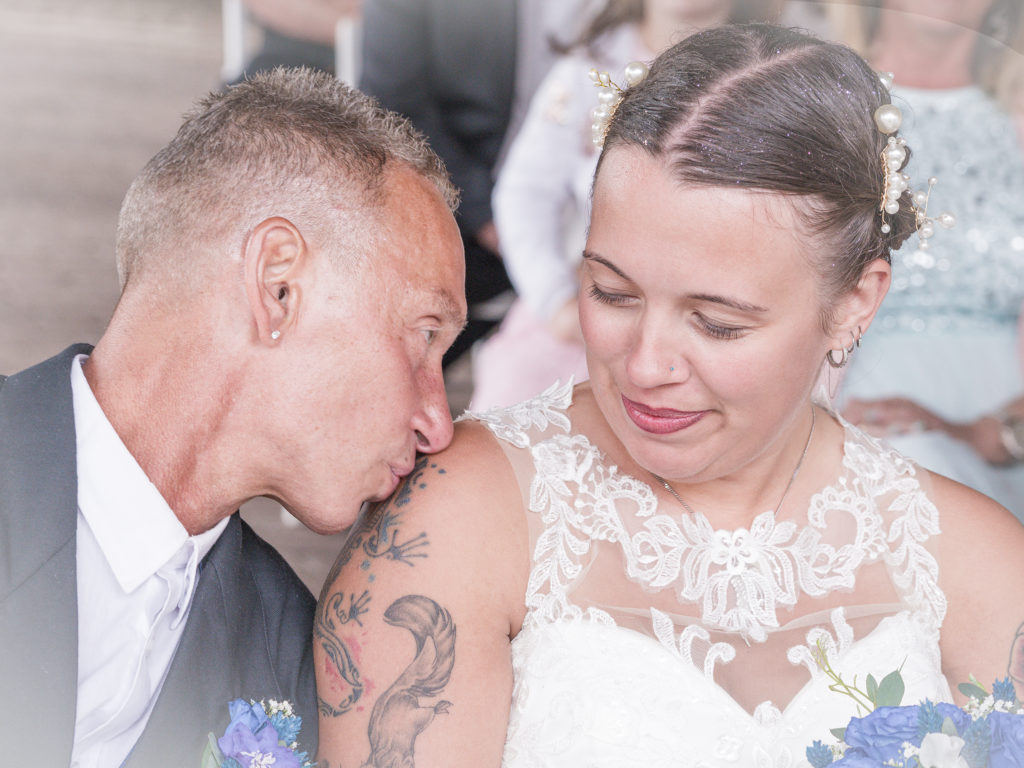 Bräutigam küsst Braut liebevoll auf die Schulter beim After-Wedding-Shooting – Hochzeitsfotografie im Grünen