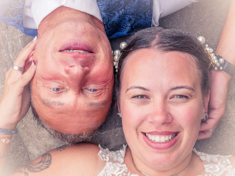 Brautpaar liegt Kopf an Kopf beim After-Wedding-Shooting – Hochzeitsfotografie im Grünen